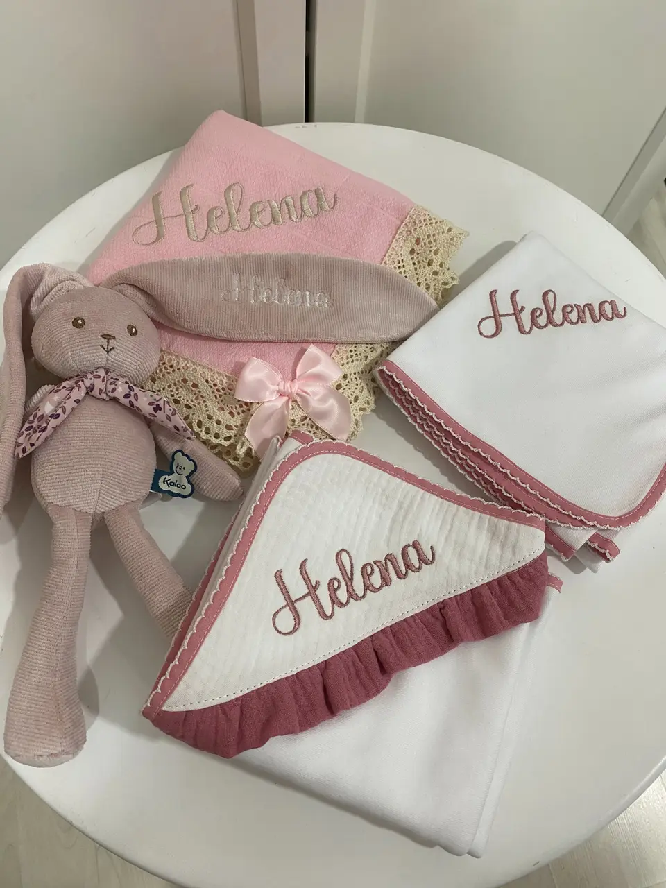 Conjunto Helena: fraldas de pano e toalha com o nome bordado em rosa-velho, com laço e um coelho de peluche.